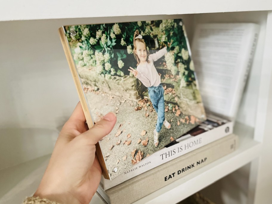 hand holding bamboo wood panel picture on books