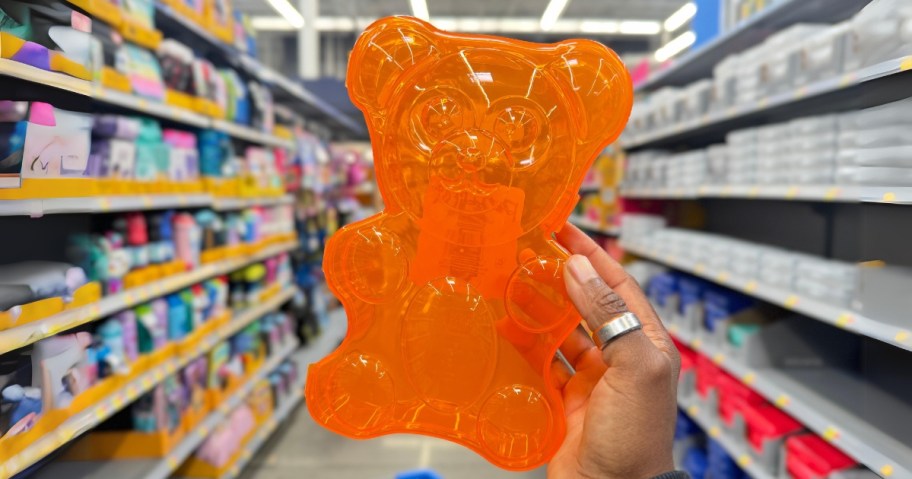 hand holding an orange gummy bear shaped plastic pencil case in a store aisle