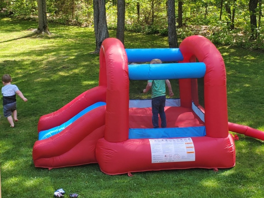 bright red and blue Radio Flyer kid's bounce house in a backyard with kids playing inside and outside it