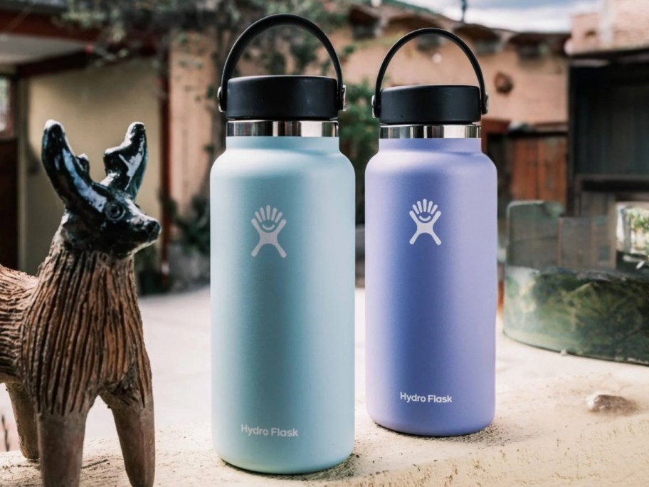 hydro flask large water bottles in Dew and Lupine sitting outside next to a wood deer figure