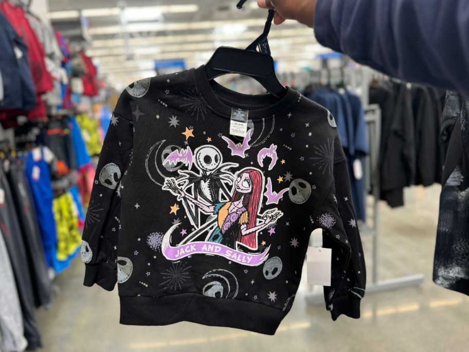 hand holding a black kid's sweatshirt with Jack & Sally from Nightmare Before Christmas on it