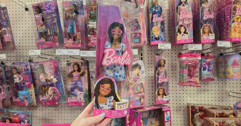 A person holding a Barbie Fashionistas Doll with Down Syndrome in a store