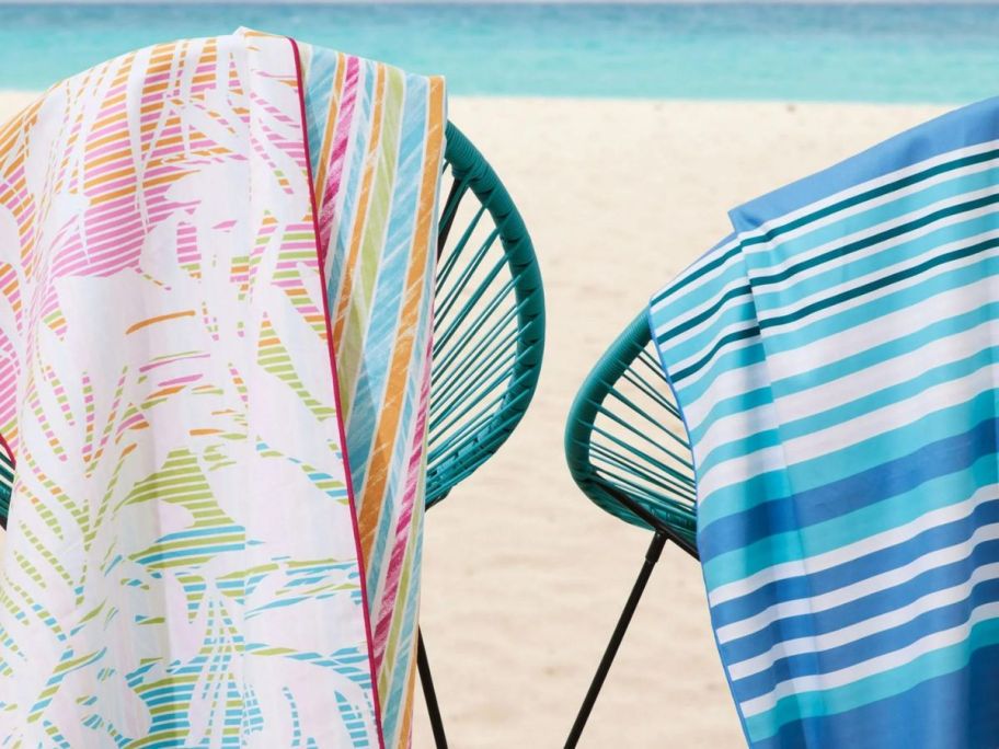 2 chairs on the beach facing the water with towels upon them