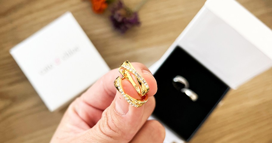 hand holding a set of gold hoop earrings