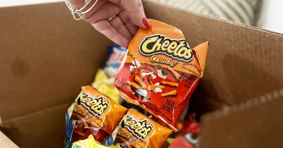 grabbing bag of cheetos from cardboard box