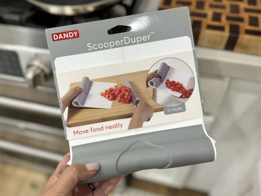 hand holding Dandy Folding Cutting Board Scraper in package