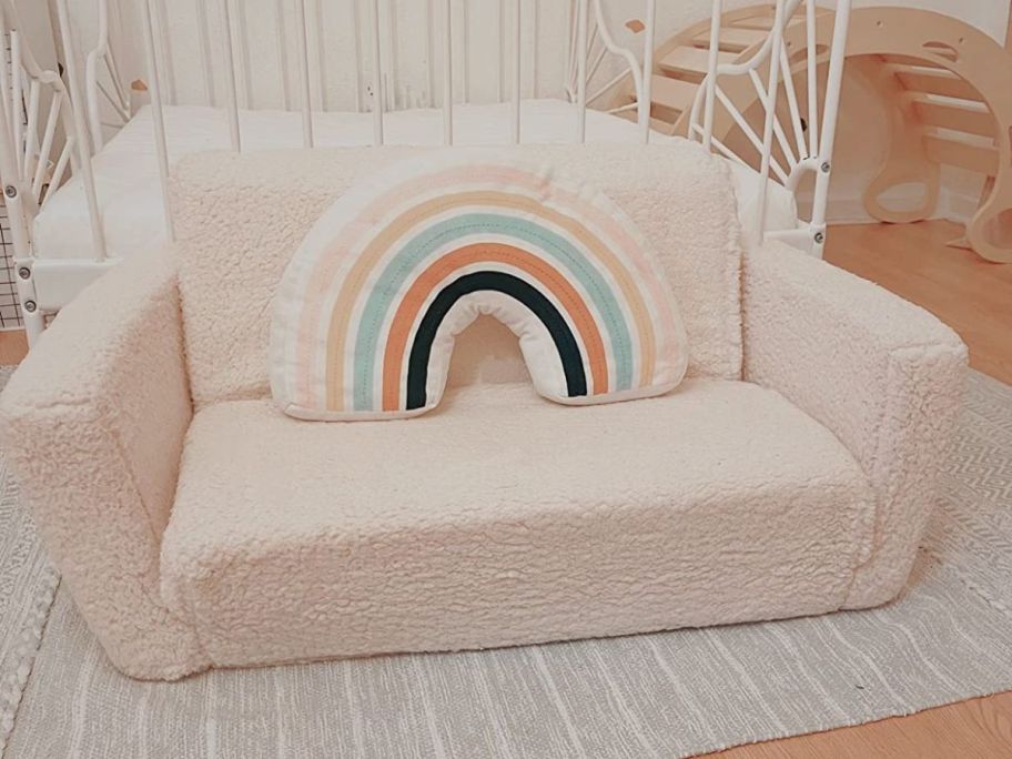 Delta Children's Cozee Flip-Out Sherpa 2-In-1 Convertible Sofa as a sofa with a rainbow pillow on it