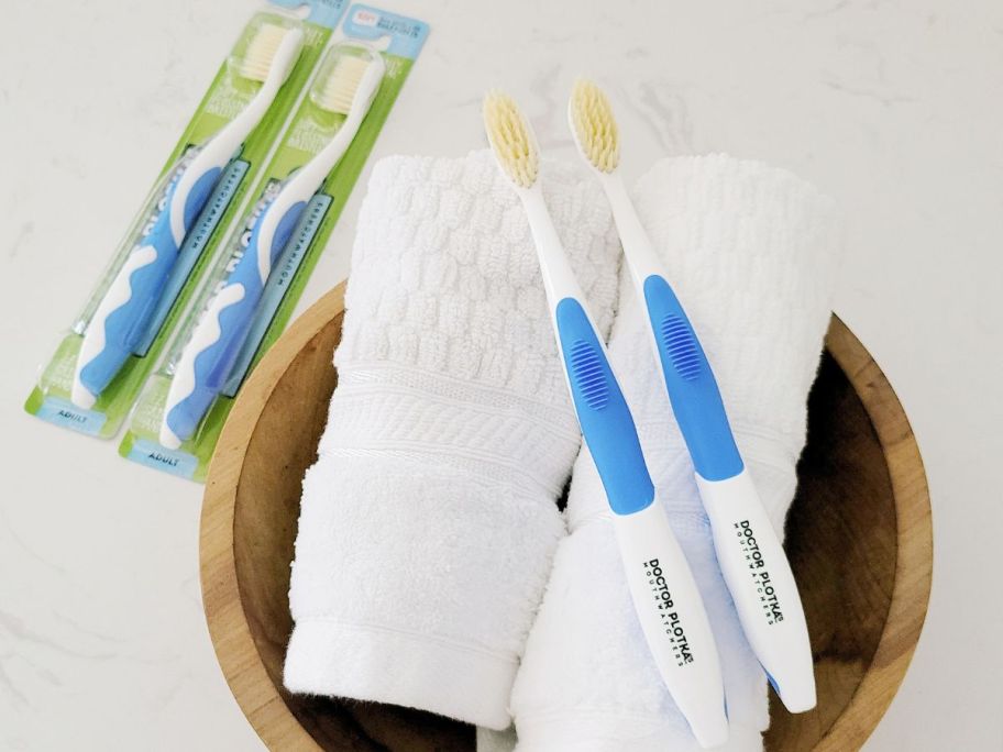 2 Dr Plotkas Mouthwatchers Toothbrushes on rolled towels with two oter toothbrushes still in the packaging