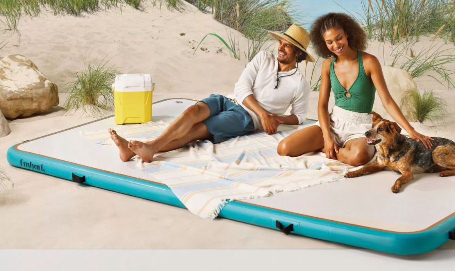 a couple on a beach sitting on an inflatable air dock