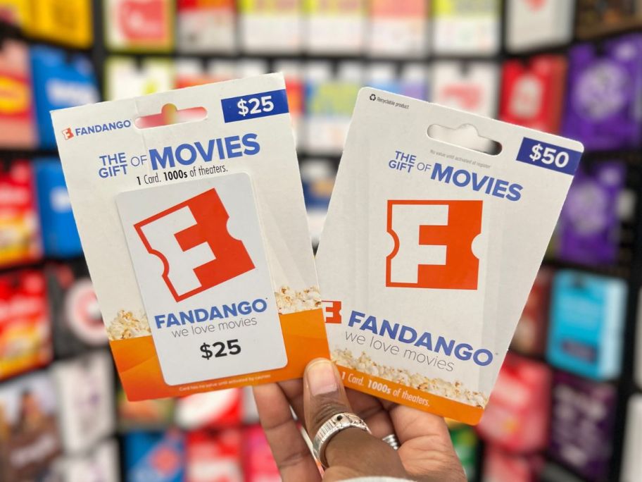 Hand holding up a $25 and $50 Fandango Gift Card