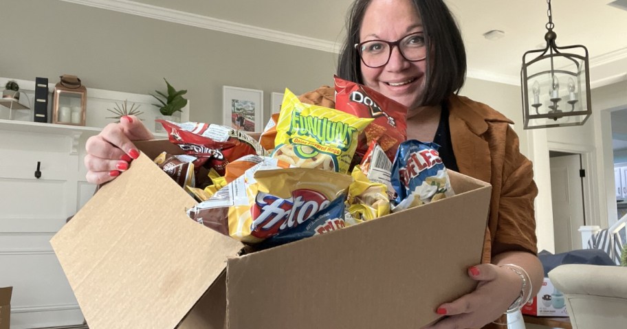 woman holding box full of frito-lay snack bags of chips
