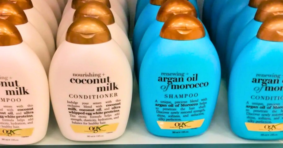 white and gold and blue and gold bottles of OGX shampoo and conditioners on a store shelf