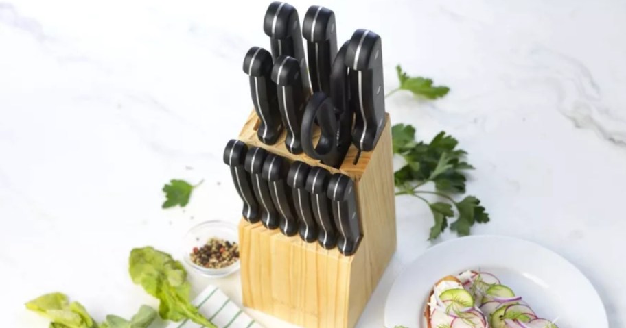 knife set with black handles in a wood block on a kitchen counter, food scraps around it