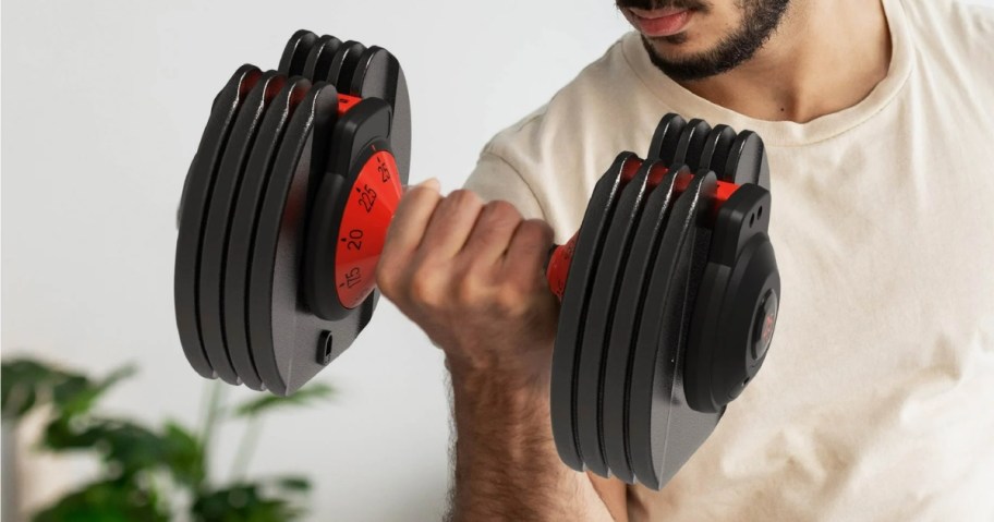 man using a black and read adjustable weight dumbbell to work out