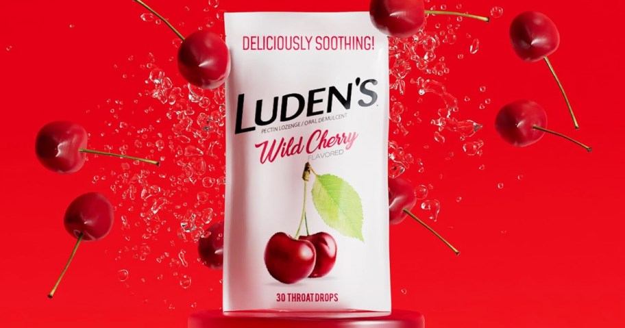 white bag of Luden’s Wild Cherry Throat Drops on red background surrounded by cherries