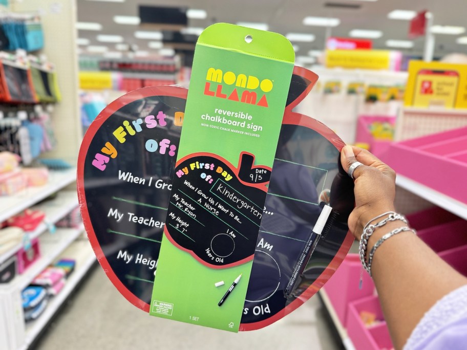 hand holding up an apple-shaped first day of school chalkboard sign