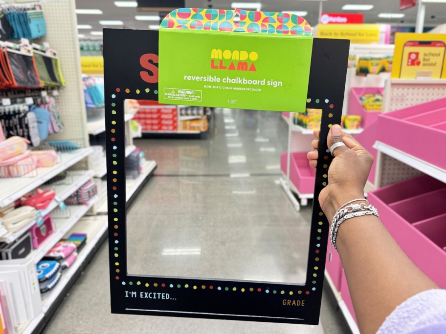 hand holding up a chalkboard first day of school photo frame