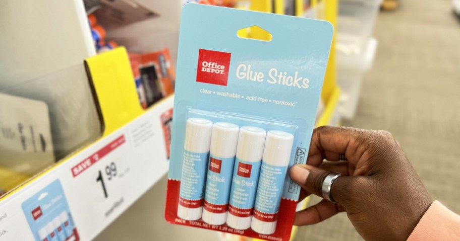 hand holding up a pack of Office Depot Glue Sticks in store