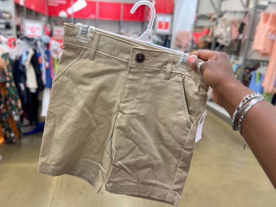 Hand holding up a hanger with a pair of Old Navy Uniform Shorts on it