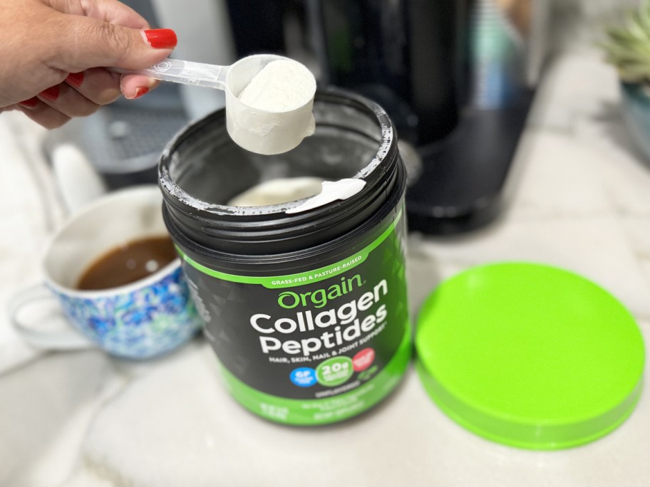 hand taking a scoop of Orgain Hydrolyzed Collagen Peptides from black jar
