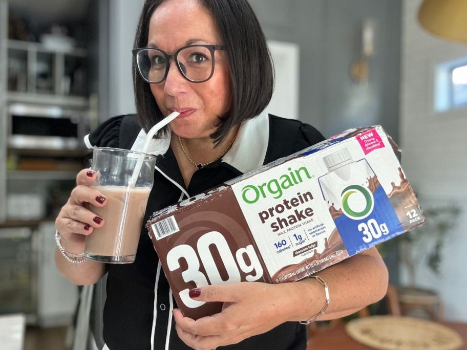 Woman holding a box of Organ Shakes while drinking from a glass with a straw