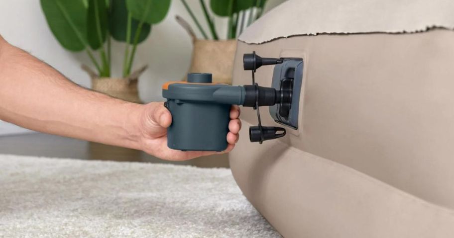 A person inflating a mattress with an electric air pump 