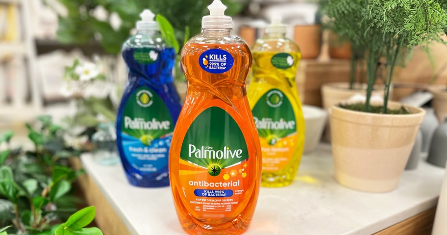 blue, orange, and yellow bottles of Palmolive dish soaps on white table