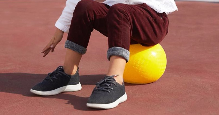 girl sitting on yellow ball on playground