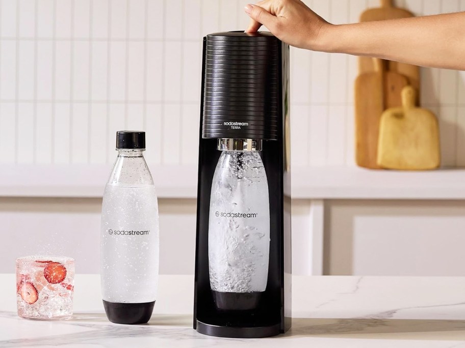 person making sparkling water in sodastream machine