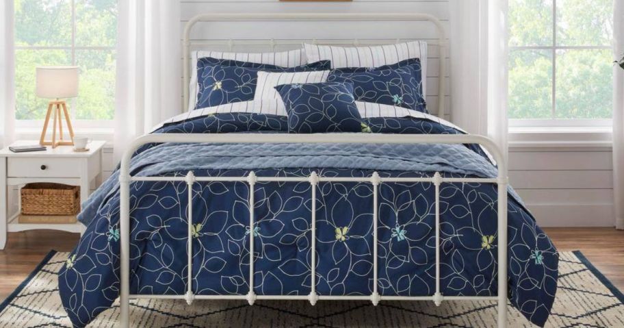A bed with a blue, floral comforter