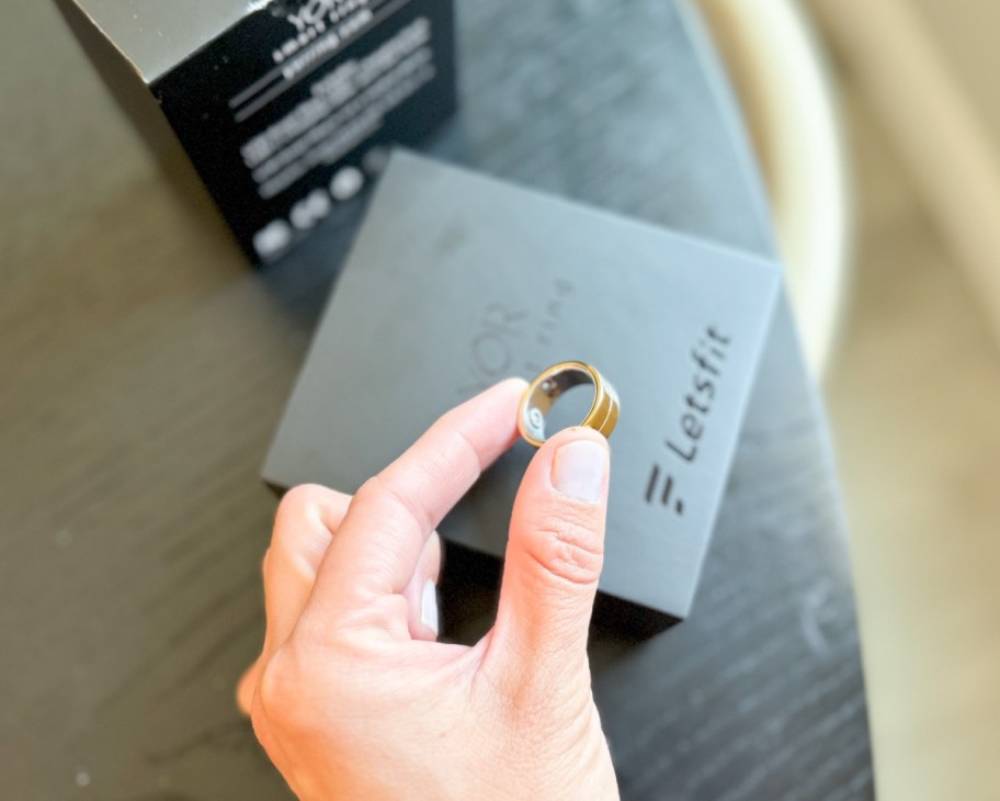 fingers grabbing smart ring on box