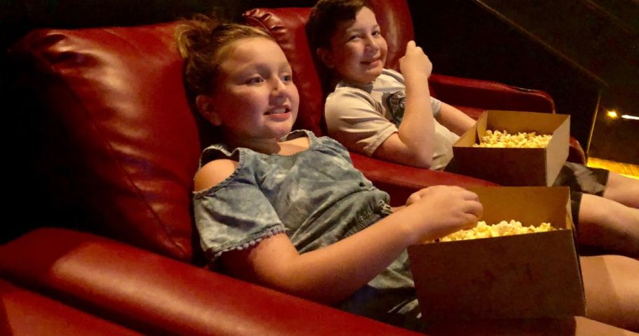 kids watching movie in amc theater with popcorn in laps