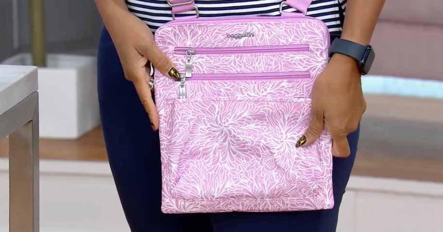 woman holding pink and white baggallini crossbody bag