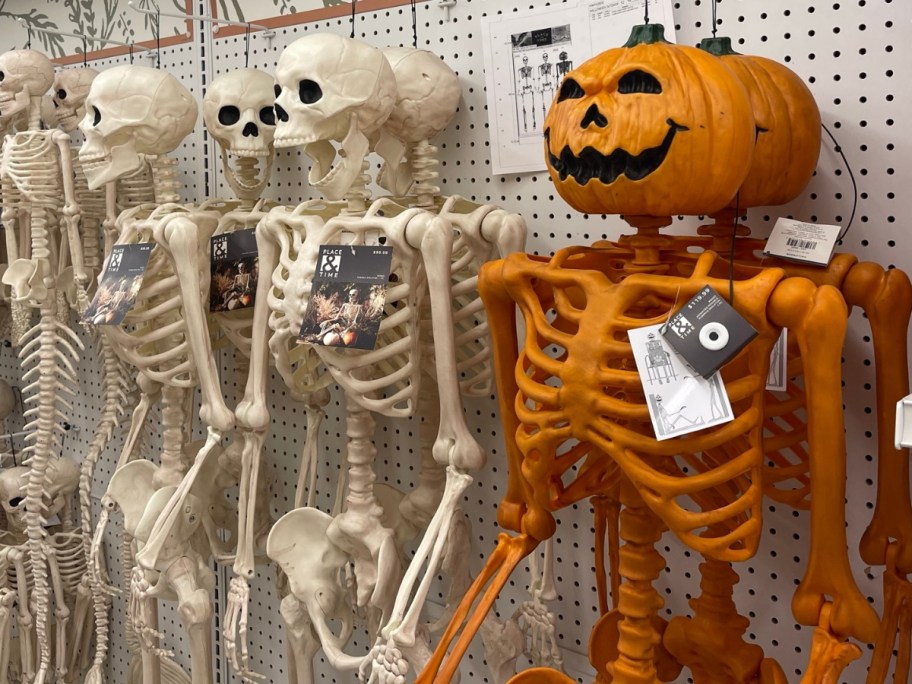 white skeletons and orange pumpkin head skeletons Halloween decor hanging on display in a store