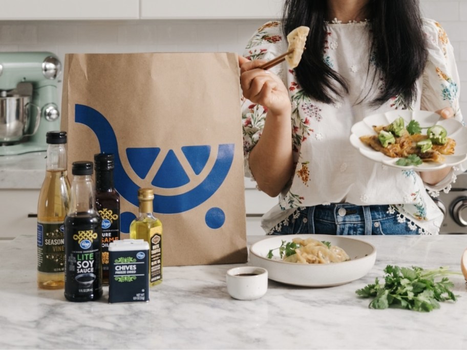 woman eating food out of a kroger shopping bag