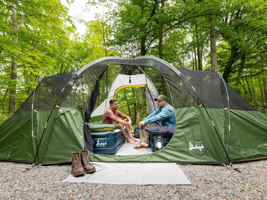 2 men sitting inside a large green dome tent, the top rain cover off, 