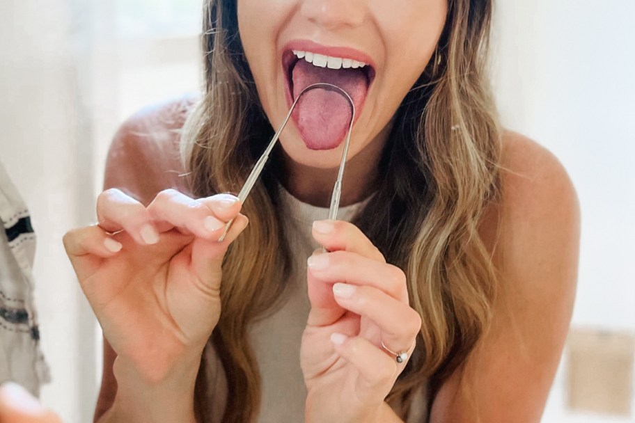 woman using tongue scraper in mirror