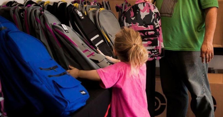 girl choosing a backpack out of an assortment