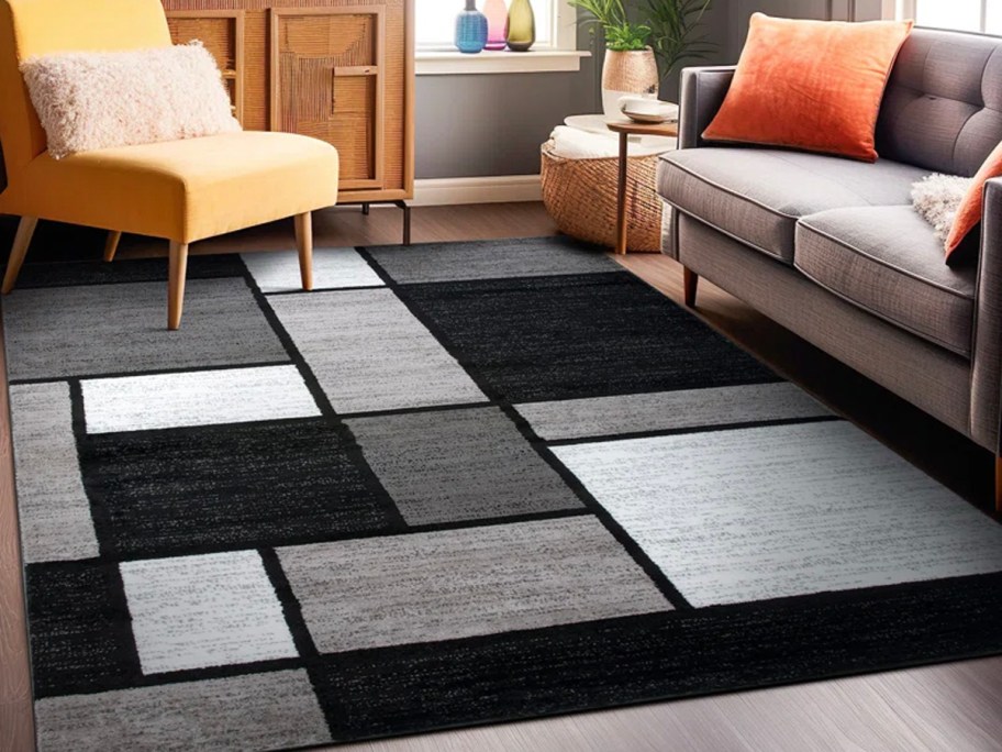 black and gray geometric rug next to yellow chair 