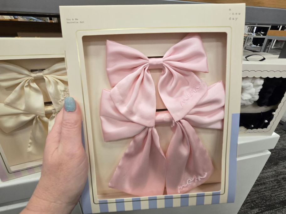 A person holding a box including pink hair bows