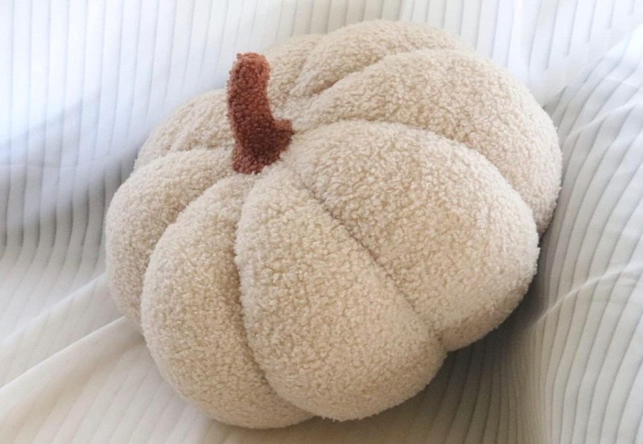 cream pumpkin pillow on white sheet