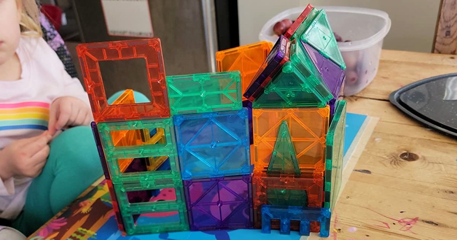 girl playing with magnetic building tiles on table