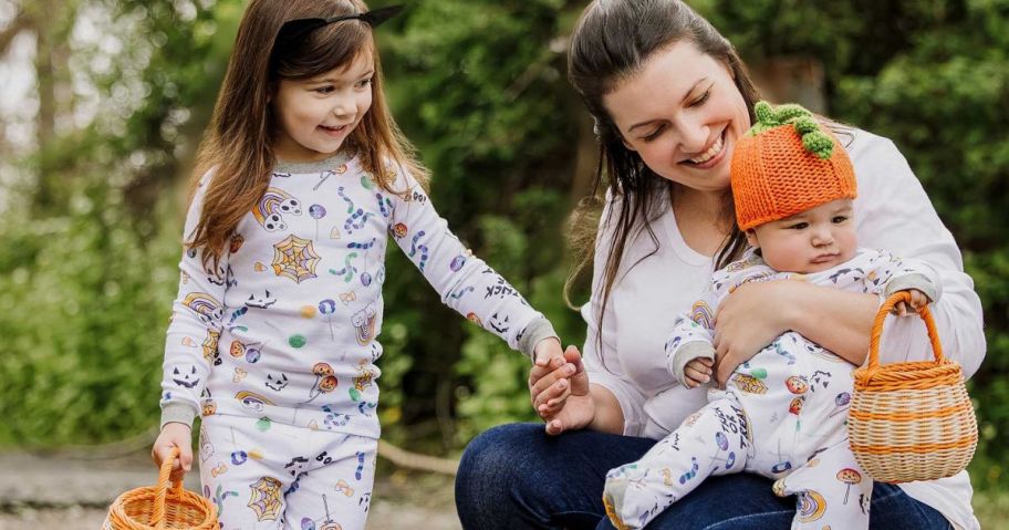 A mom with a baby and a little girl wearing Burt's Bees Halloween pajamas