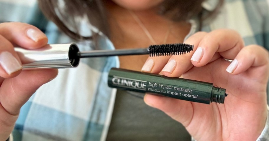 woman holding a tube and wand of Clinique High Impact Mascara