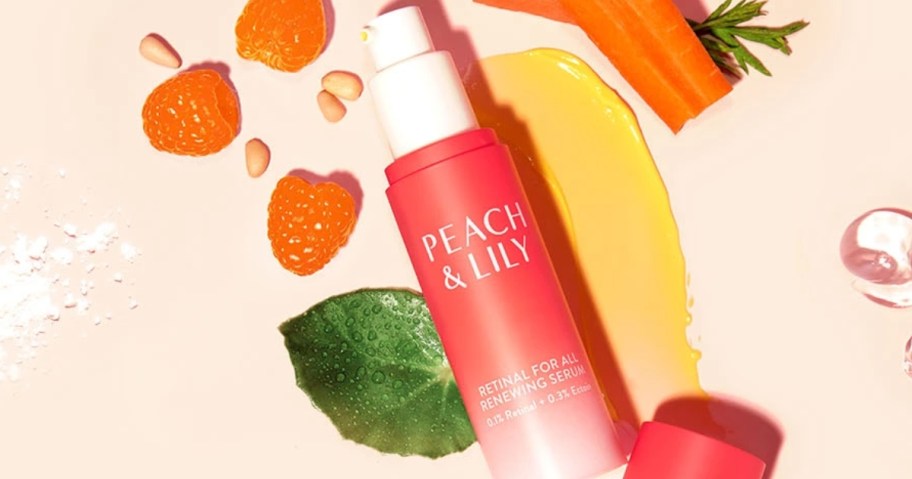 orange and white bottle of Peach & Lily Retinal For All Renewing Serum surrounded by the serum and various fruit slices