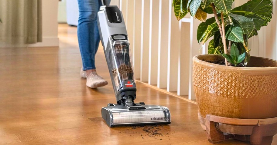 woman using a black Bissell cordless wet/dry vacuum on a hardwood floor