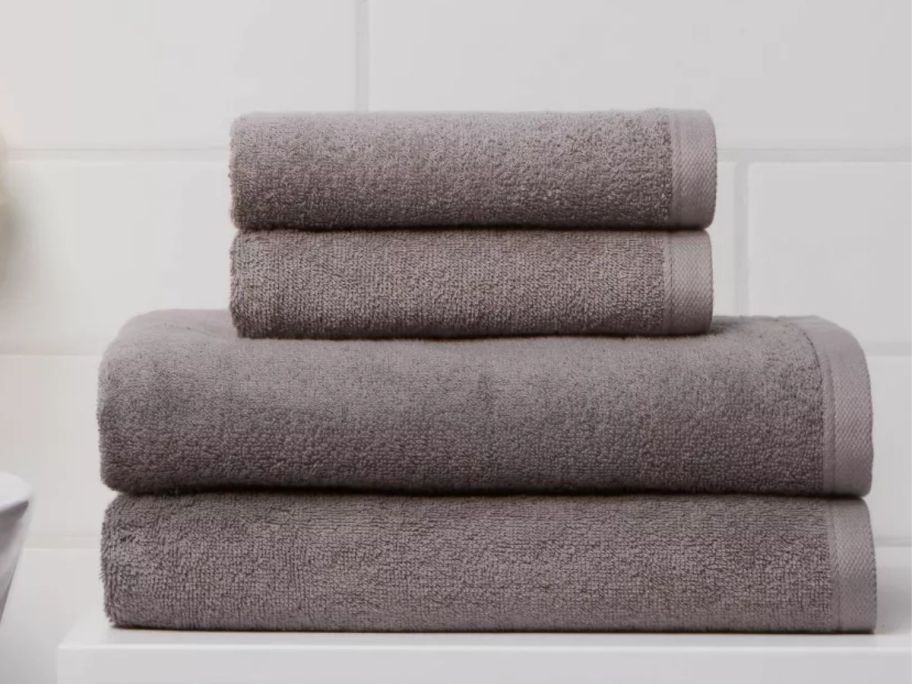 a set of 2 grey bath towels and 2 grey hand towels stacked on a bathroom counter