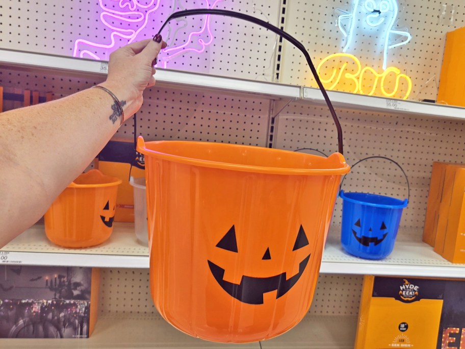 hand holding up a large orange trick or treat bucket