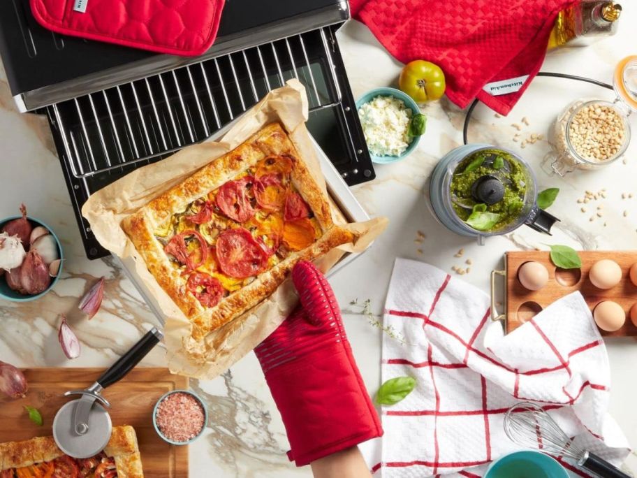 person using KitchenAid Quilted Cotton Terry Cloth Oven Mitt & Pot Holder Set in Passion Red in kitchen