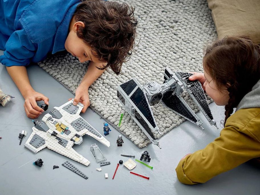 Two kids playing with a LEGO Star Wars Mandalorian Fang Fighter vs. TIE Interceptor